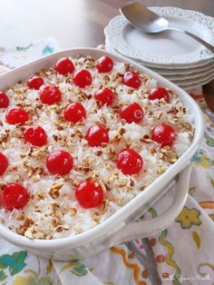 a casserole dish with cherries and nuts in it on a floral tablecloth