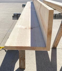 a wooden bench sitting on the side of a road next to a parking lot with no one around it