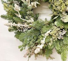 a green wreath with white flowers and greenery