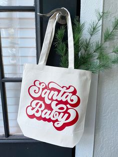 Santa Baby tote bag! A perfect holiday season accessory! 13x13.5 with a 9.5" strap drop Each item is handmade and may vary slightly.  No returns or exchanges accepted however if there is any issue with your item upon arrival, please contact me and I will work with you to fix it!  Spot cleaning is best. If you must wash, turn inside out and hang to dry! Christmas Tote Bag As Gift, Christmas Tote Bag Gift, Christmas Gift Tote Bag, Red Christmas Bag For Everyday Use, Red Christmas Bags For Everyday Use, Red Bag For Everyday Use And Christmas, Tote Shoulder Bag For Gifts, Christmas Rectangular Bag, Baby Tote Bag