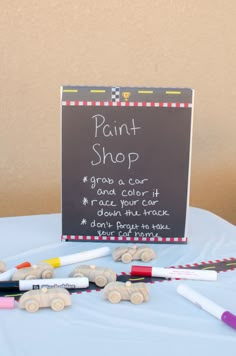 there is a sign that says paint shop and some crayons on the table