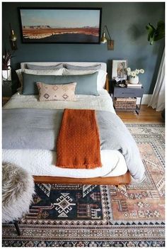 a bedroom with a large bed, rugs and pictures on the wall above it