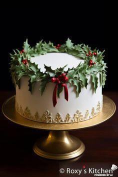 a christmas cake decorated with holly leaves and red berries on a gold plated platter