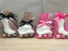 three bags filled with white and pink baby booties sitting on top of a wooden table