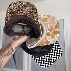 a person holding up five hats in front of a wall with pictures on it and the words wildflowers written on them