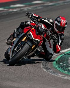 a man riding on the back of a red motorcycle down a race track next to a green and white line