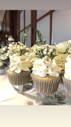 cupcakes with white frosting and flowers on a table