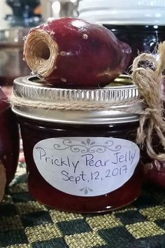 an apple jam in a glass jar with some apples next to it on a table