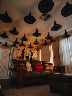 a living room filled with furniture and lots of black hats hanging from the ceiling above