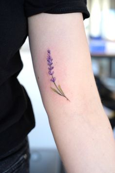 a small lavender flower tattoo on the arm