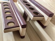 two wooden benches with holes in them sitting on a table next to another bench that is made out of wood