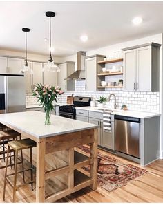 a kitchen with stainless steel appliances and white counter tops, wooden flooring and an area rug