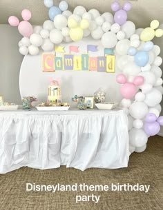 there is a table with balloons and decorations on it for a birthday party at the disneyland theme park