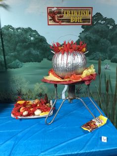 a blue table topped with two large metal bowls filled with fruit and veggies