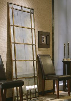 two chairs and a table in front of a large glass window with candles on it