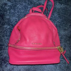 This beautiful Michael Kors Rhea backpack is perfect for any stylish woman. With a stunning Ultra Pink exterior color and Gold hardware, this bag is sure to turn heads. The bag features a zip closure and a gold handle/strap color that matches the exterior perfectly. The lining color is also Gold, which adds a touch of elegance to the bag. Made of high-quality leather, this bag is durable and perfect for everyday use. The bag is small in size, making it perfect for carrying your essentials. The Michael Kors brand is known for its quality and style, and this bag is no exception. Michael Kors Rhea Backpack, Medium Backpack, Gold Handles, Gold Leather, High Quality Leather, Pink Gold, Stylish Women, Gold Hardware, Pink And Gold