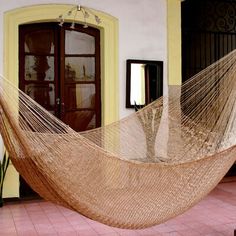 a hammock hanging in front of a yellow door on a brick patio area