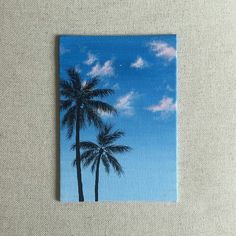 a painting of two palm trees against a blue sky with white clouds in the background