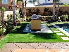 a backyard with grass and landscaping surrounding the pool