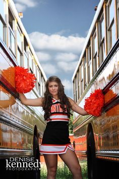 a cheerleader standing in front of two buses with pom poms on their hands