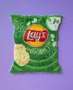 an image of a bag of chips on a purple surface with green and white beads