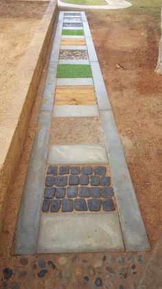 an outdoor walkway made out of concrete blocks and bricks with grass growing in between them