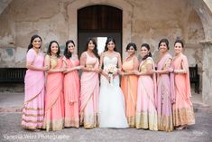 a group of women standing next to each other in front of a building wearing different colored dresses