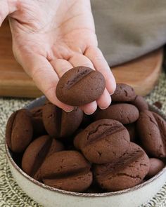 a person reaching for some chocolate cookies in a bowl