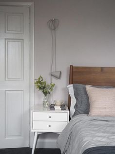 a bedroom with a bed, night stand and lamp on the side table next to it