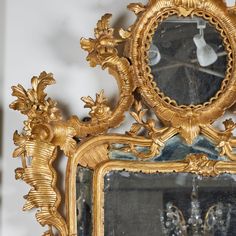 an ornate gold framed mirror sitting on top of a table