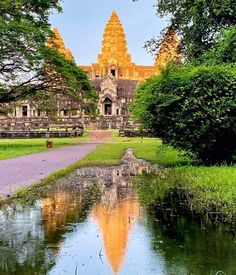 a large building sitting on top of a lush green field next to a river filled with water