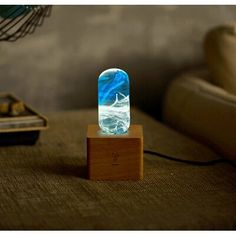 a blue and white glass object sitting on top of a wooden stand in front of a couch