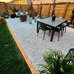 an outdoor patio with gravel and wooden fenced in seating area next to the back yard