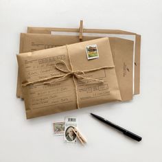 two brown envelopes tied with twine on top of each other next to a pen and stamp