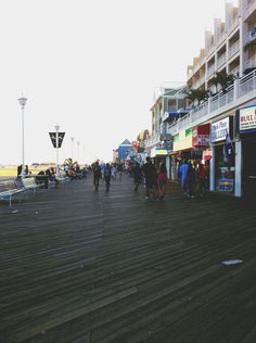 people are walking on the boardwalk in front of shops