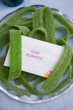 a plate filled with green seaweed next to a white paper sign that says under the sea birthday party ideas