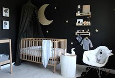 a baby's room decorated in black and white with stars on the wall, crib, rocking chair, and bed