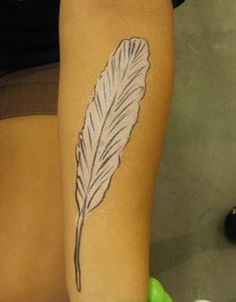 a woman with a tattoo on her arm has a white feather painted on the side of her leg