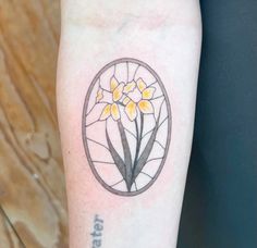 a tattoo on the arm of a woman with yellow flowers in a circular frame and words below it