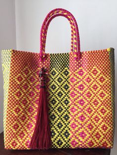 a yellow and red bag with a tasseled handle sitting on top of a table