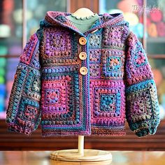 a crocheted jacket sitting on top of a wooden table