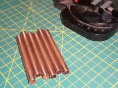 four pieces of metal sitting on top of a green cutting board next to a machine