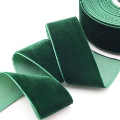 two rolls of green velvet ribbon on white background