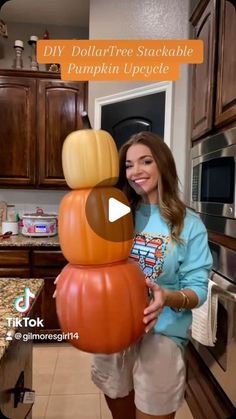 a woman standing in front of a kitchen counter holding a large pumpkin shaped object with the words diy dollartree stackable pumpkin upside down