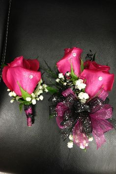 two pink roses are sitting on a black leather surface