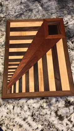 a wooden cutting board sitting on top of a marble counter next to a knife holder