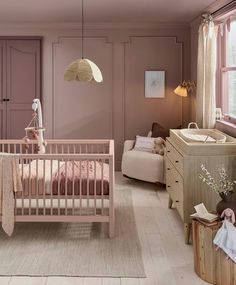 a baby's room with pink walls and wooden furniture, including a crib