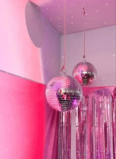 two disco ball chandeliers hanging from the ceiling in a room with pink walls