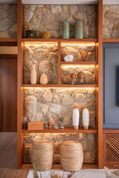 a stone wall with some vases and other items on it in front of a flat screen tv