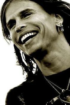 a black and white photo of a man with dreadlocks on his head smiling